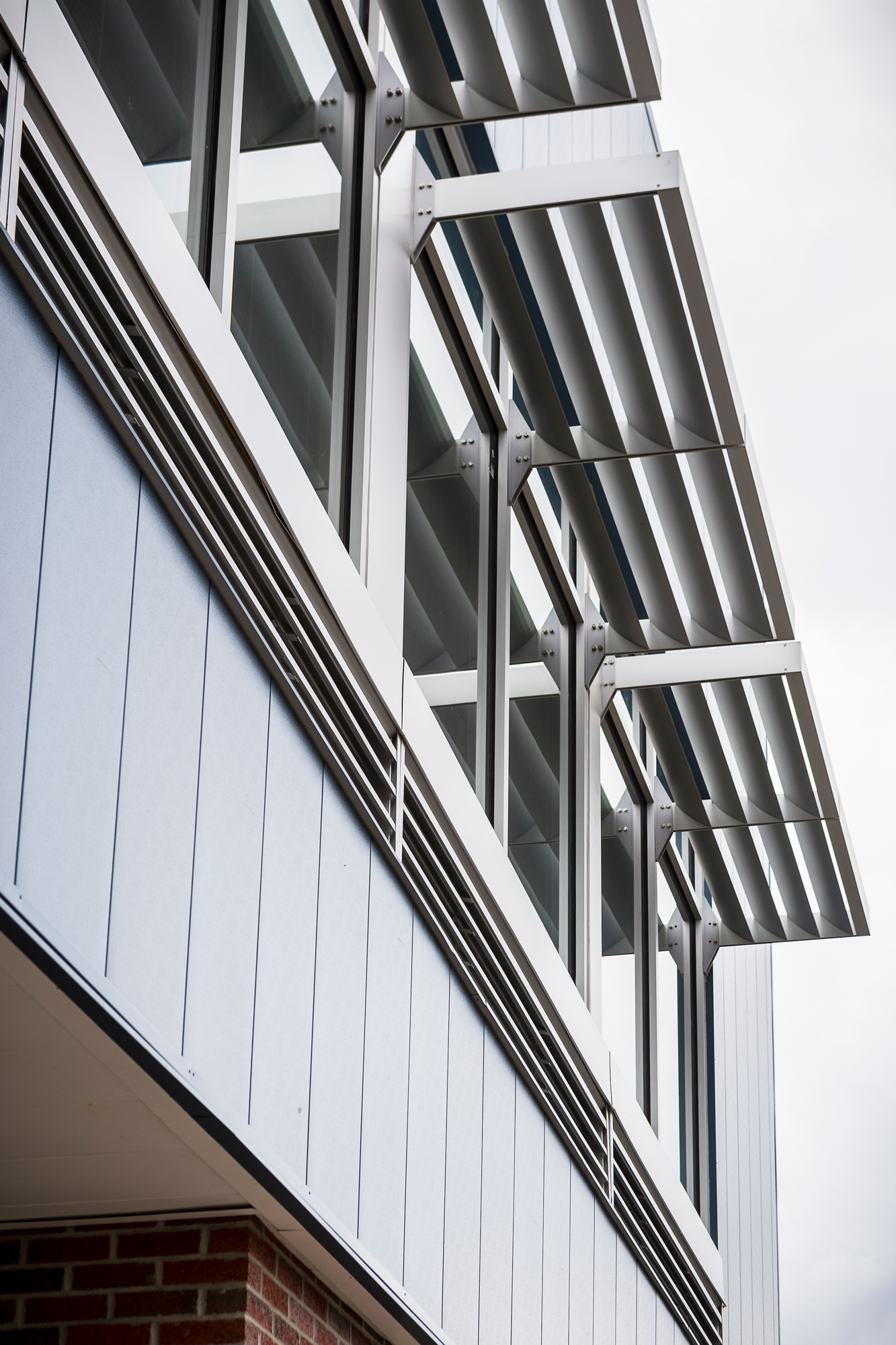 Exterior metal wall panels with projecting sunshade louvers above windows on a modern building facade